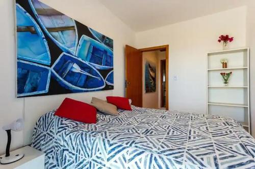 Un dormitorio con una cama con almohadas rojas y una pintura en MARCOLINI - Unamar, Conforto em frente a Praia! en Cabo Frío