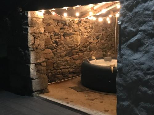 a room with a stone wall and a bathtub with lights at Mournes Family Cottage with Hot Tub in Hilltown