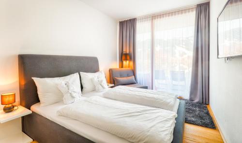 a bedroom with a bed and a chair and a window at Residence Bellevue - incl Summercard in Zell am See