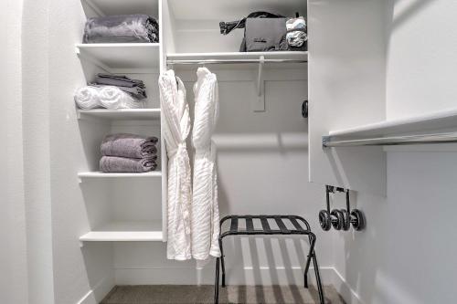 a closet with white shelves and a chair and towels at Private Rooftop Terrance - King Beds - Walk Score 81 & Parking 4014 in Scottsdale