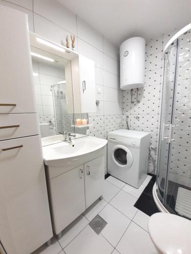 a white bathroom with a sink and a washing machine at Apartman Prenj in Konjic