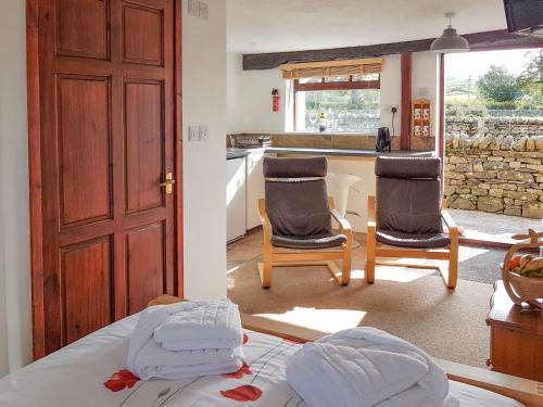 a bedroom with two chairs and a kitchen with a counter at The Snug - Uk42088 in Sedbergh