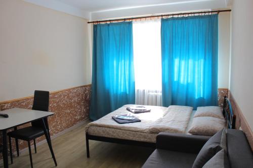 1 dormitorio con 1 cama con cortinas azules y mesa en Uneed Rooms Harbour, en Kiev