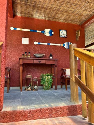 a room with a table and a red wall at Pousada Preciosa do Arraial - com Natura e L'Occitane - recém inaugurada in Arraial d'Ajuda