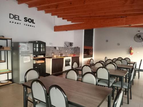 a dining room with tables and chairs and a kitchen at DEL SOL APART TERMAL I in Termas de Río Hondo