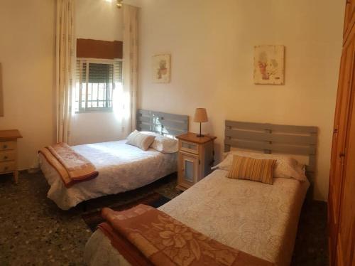 1 dormitorio con 2 camas, mesa y ventana en CHALET con ENCANTO en SIERRA CORDOBESA. WIFI en Cerro Muriano