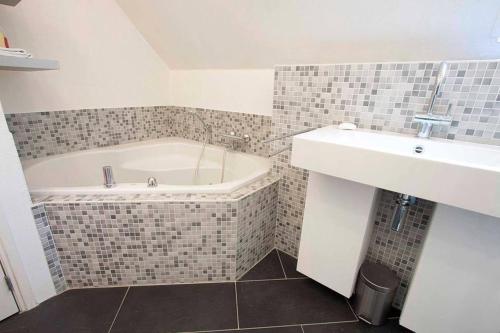 a bathroom with a bath tub and a sink at B&B Bij Arjan in Terborg