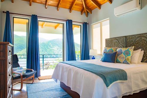 Jost Van Dyke的住宿－Jost Van Dyke, BVI 3 Bedroom Villa with Caribbean Views & Pool，一间卧室配有一张蓝色窗帘的床和一个阳台