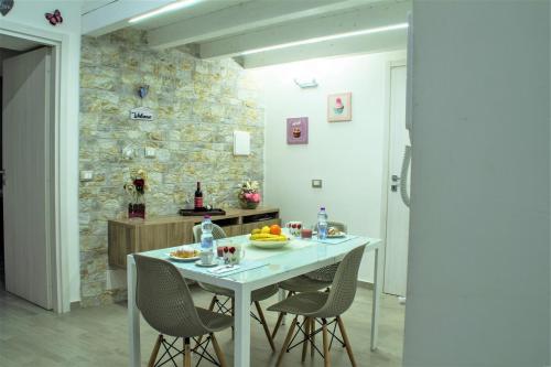 cocina con mesa, sillas y pared de piedra en Casa Vacanza Al Massimo, en Palermo