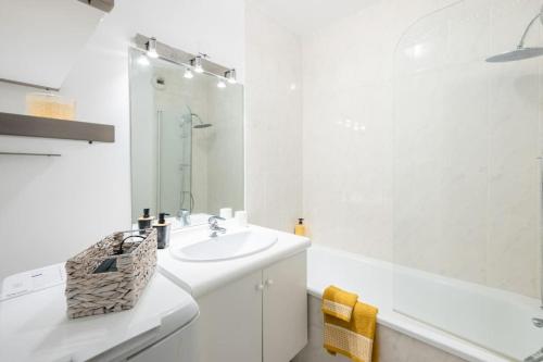 a white bathroom with a sink and a tub at Le Nid Douillet T2, Wifi, Parking privé gratuit in Lille