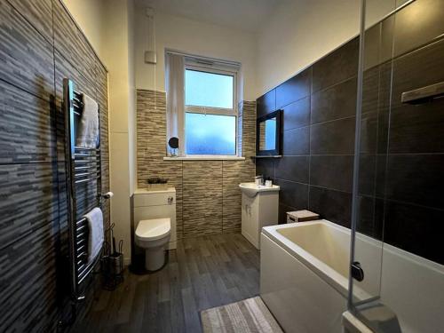 a bathroom with a tub and a toilet and a window at Stratford Stay - sleeps up to 9 near City Centre with parking in Birmingham
