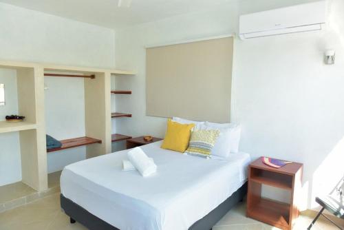 a bedroom with a large white bed with yellow pillows at Telchac Beach House in Telchac Puerto