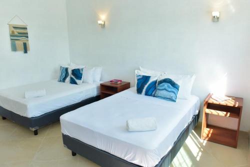 two beds with blue pillows in a room at Telchac Beach House in Telchac Puerto