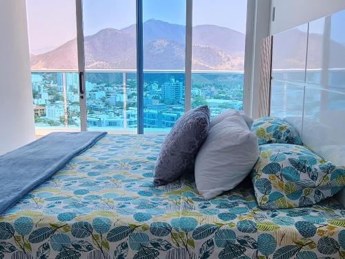 a bedroom with a bed with pillows and a large window at Apartamento frente al mar en Reserva del Mar apto 1829 in Gaira