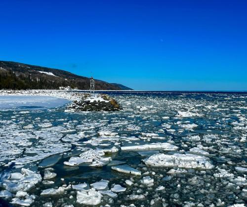 a large body of water with ice and a lighthouse at Auberge musicale Pour un Instant in La Malbaie