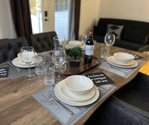 a wooden table with plates and wine glasses on it at Auberge musicale Pour un Instant in La Malbaie