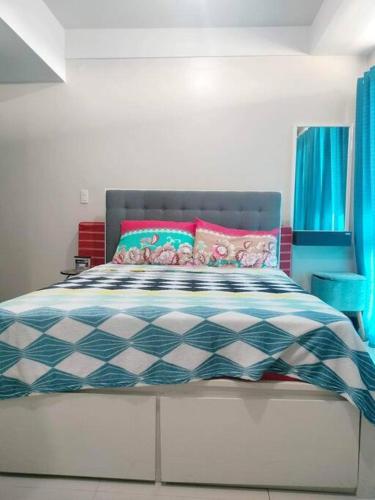 a bedroom with a bed with blue and pink pillows at Cubao Manhattanheights U31N TB, Studio Unit in Manila