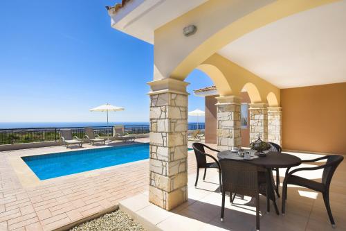 a patio with a table and chairs and a swimming pool at Club St. George in Paphos City
