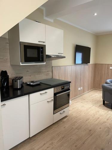 a kitchen with white cabinets and a microwave at Hotel Select Suites & Aparts in Mönchengladbach