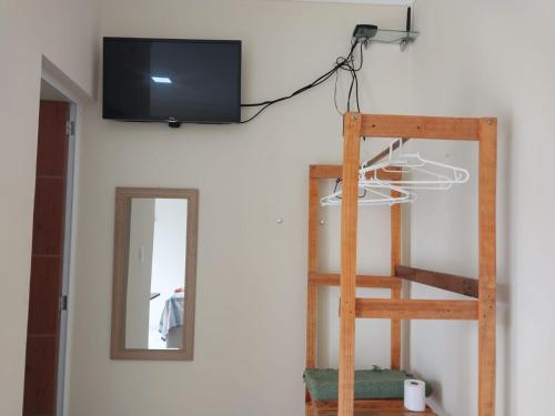 een televisie aan een muur naast een ladder bij Suíte Porto das Dunas in Salvador