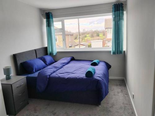 a bedroom with a bed with purple sheets and a window at Cosy Brighouse 3 bed house-Great for contractors in Brighouse