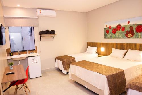 a hotel room with two beds and a desk at Fiori Suítes in Goiânia