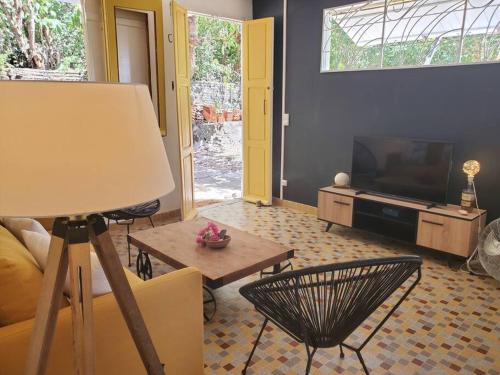 a living room with a couch and a table and a television at Villa Sunshine in La Trinité