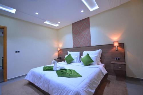 een slaapkamer met een groot wit bed met groene kussens bij RESIDENCE CENTROSUIT in Laayoune