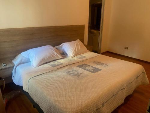 łóżko z białą pościelą i poduszkami w pokoju w obiekcie rosarigasino w mieście Rosario