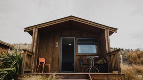 a small cabin with a porch and a table and chairs at Lakes Edge Holiday Park in Lake Tekapo