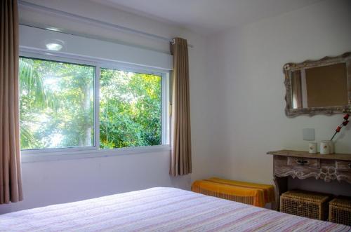 une chambre avec un lit et une grande fenêtre dans l'établissement Ilhabela - Praia do Curral - Casa em condomínio, à Ilhabela