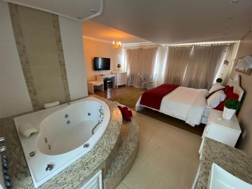 a bathroom with a tub and a bedroom with a bed at Hotel Domo in Prudentópolis
