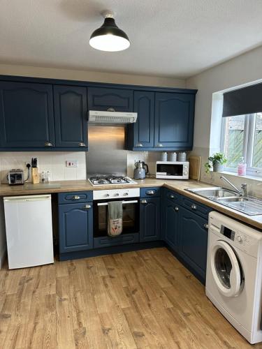 eine Küche mit blauen Schränken und einer Waschmaschine in der Unterkunft 6 Stephenson Way in York