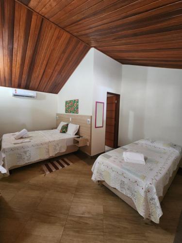 a bedroom with two beds and a wooden ceiling at Pousada Sítio do Sossego in Monte Alegre do Sul