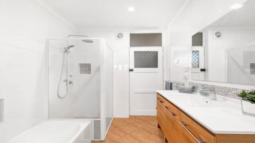 a white bathroom with a shower and a sink at Tradewinds in Callala Bay