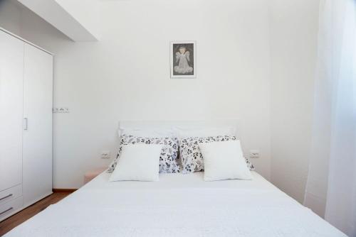 a white bedroom with a white bed with two pillows at Apartman Kiara in Rogoznica