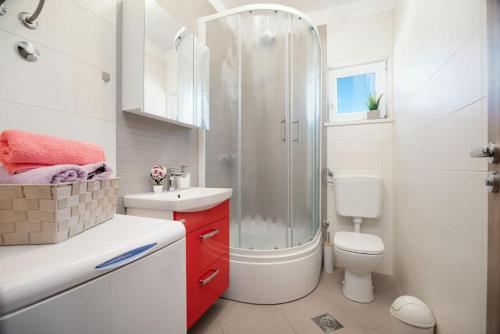 a white bathroom with a shower and a toilet at Apartman Kiara in Rogoznica