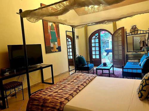 um quarto com uma cama e uma televisão num quarto em Villa Charles - île de Gorée em Gorée