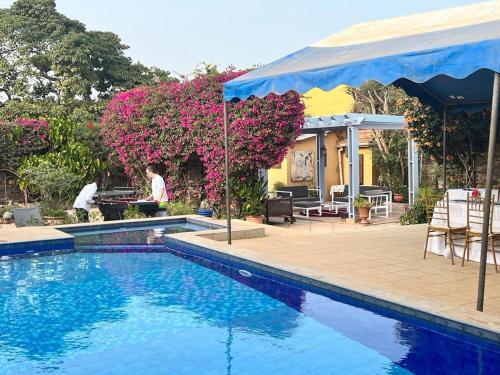 a swimming pool with a woman sitting at a table next to a house at Villa Charles - île de Gorée in Gorée