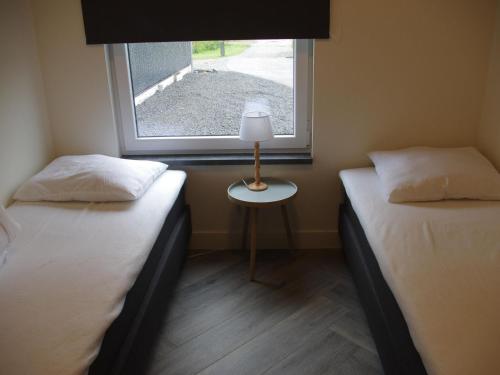 2 camas individuais num quarto com uma janela em Beautiful bungalow with bath, located in a holiday park near the city of Alkmaar em Hensbroek