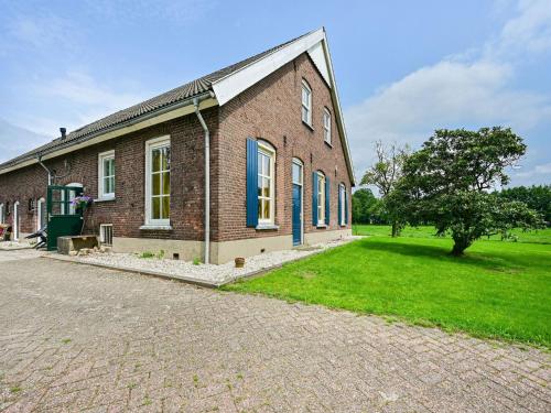 a brick building with a grass yard next to a tree at Cozy Countryside Getaway in De Heurne