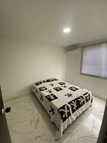 una camera da letto con un letto con un piumone bianco e nero di Cómodo apto 201 muy cerca a C.C. Unicentro Cúcuta a Cúcuta