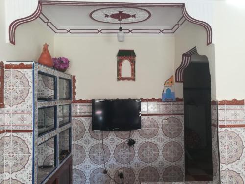 La salle de bains est pourvue d'un mur carrelé et d'une télévision murale. dans l'établissement Dar Abdlouahed, à Chefchaouen