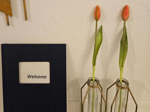 dos jarrones con flores en ellos junto a una tarjeta de bienvenida en B&B Apartment Amsterdam Schiphol Airport en Hoofddorp