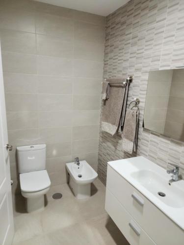a white bathroom with a toilet and a sink at Casa Marta. in Granadilla de Abona