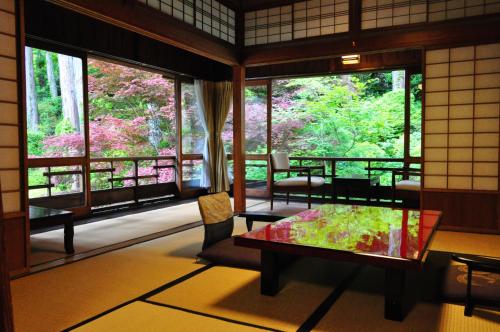 a room with a table and chairs and windows at Yunoshimakan in Gero