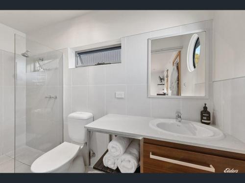 a white bathroom with a sink and a toilet at Salt Box Hideaway in Strahan