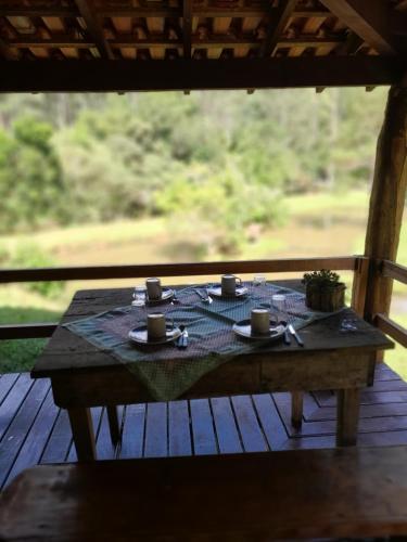einen Tisch mit Tassen und Untertassen auf einem Holzdeck in der Unterkunft Morada Vale das Águas in São Bonifácio