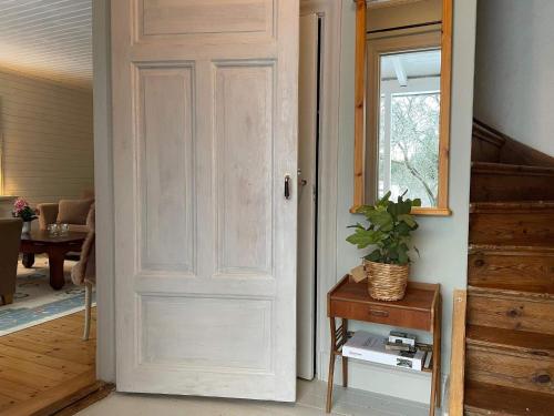 eine weiße Tür in einem Zimmer mit einer Pflanze auf einem Tisch in der Unterkunft Holiday home JÄRNA II in Järna