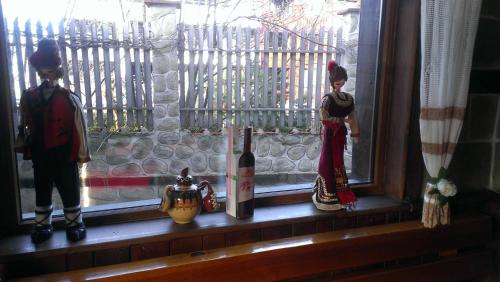 two toy figurines sitting on a window sill with wine bottles at Family Hotel Bansko Sofia in Sofia